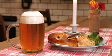 Tisch mit Glaskrug Zoigl Bier nebst Teller mit Brezel und Obazda mit Garnitur