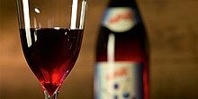 Glas mit Heidelbeerwein neben Weinflasche